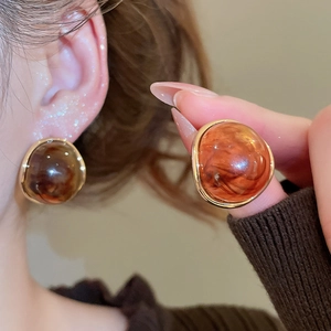 Macro shot of vintage round amber resin earrings with golden frame detail