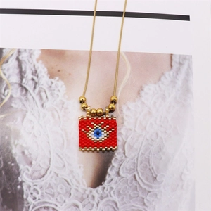 Detail of red handmade beaded evil eye pendant with tiny gold beads and a fine snake chain