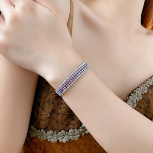 Gros plan d'un bracelet en zircon à quatre rangées de pierres violettes et blanches au poignet