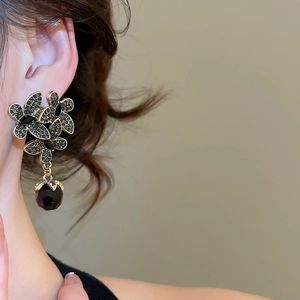 Macro detail of vintage floral earring with black petals and faceted bead on model
