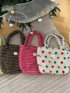 Colorful polka dot and striped plush tote bags on a woven mat with festive background