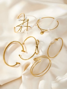 Detailed view of five 18k gold plated stainless steel bangles on beige silk background