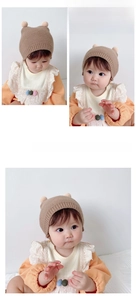 Detail view of baby winter knit hat with pom-pom ears and a lace-trimmed bib accessory