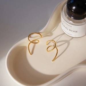 Close-up of golden spiral geometric earrings on a wave tray with elegant lighting
