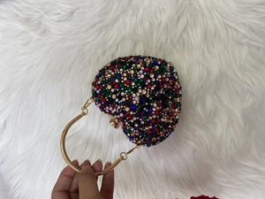 Detail of colorful rhinestones and beads on heart-shaped evening bag with gold handle