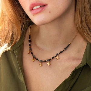 Natural stone necklace with gold star pendants worn by model in outdoor light