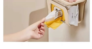 Close-up of wall-mounted tissue box showing wet wipes being pulled from a yellow lid