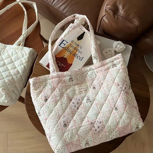 Detailed macro view of quilted tote bag with rabbit floral patterns and French woven label