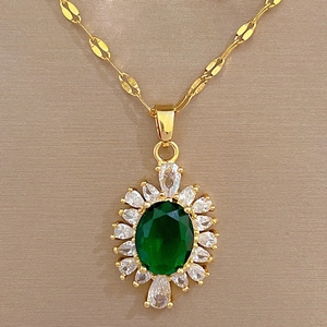 Detailed macro view of a gold-tone titanium necklace with green oval stone and white gems
