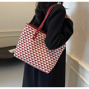 Close-up of red and white patterned tote bag with leather straps worn by a model