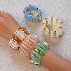 Detail of colorful acrylic beaded bracelets with gold irregular metal spacers on wrist