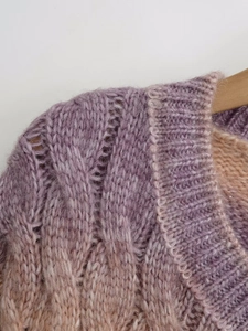 Close-up of cable-knit gradient sweater showing purple knit texture and ribbed neckline