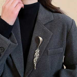 Silver geometric tassel brooch on charcoal wool suit lapel showcasing minimalist style
