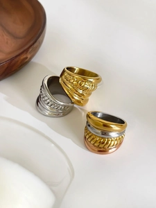 Detail of wide multi-layer rings in gold, silver, and rose gold with ribbed textures