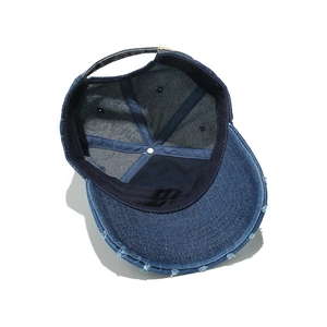 Detail view of the washed blue denim baseball cap showing distressed brim and inner seams