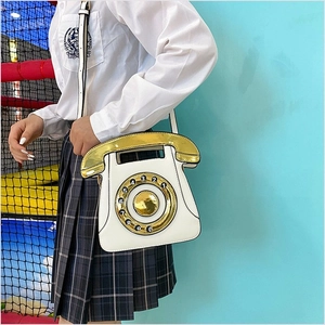 Detail of creative vintage telephone crossbody bag with metallic dial on female model