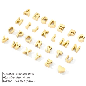 Macro shot of 26 gold stainless steel 6mm alphabet charms and a heart pendant set
