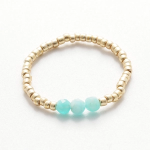 Detailed shot of handmade beaded ring with gold spheres and turquoise crystal accents