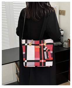 Détail du cabas en toile à carreaux rouge et noir avec ferrures dorées et petite pochette