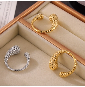 Detailed view of hammered texture on gold and silver open rings in a velvet box