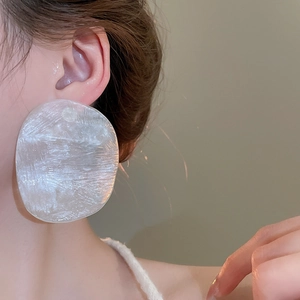 Macro detail of irregular white resin earrings featuring artistic ice-crack textures