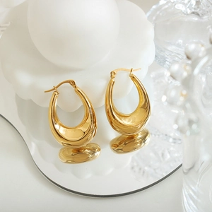 Polished gold U-shaped drop earrings displayed on a minimalist reflective base
