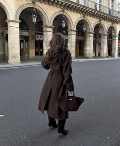 Dettaglio di un cappotto in lana marrone scuro con stivali in camoscio in strada classica