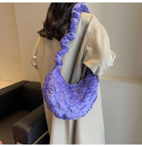 Detail of purple quilted velvet cloud bag with unique wavy shoulder strap on model