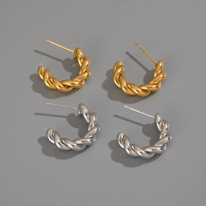 Dettaglio macro di orecchini a cerchio intrecciati in oro e argento con design a corda