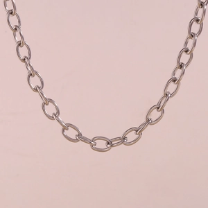 Detailed macro view of silver stainless steel chain links on a soft pink backdrop