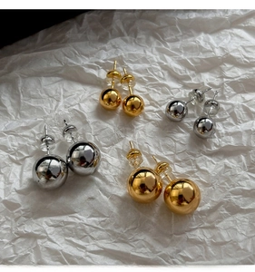 Close-up of gold and silver sphere stud earrings in two sizes with mirror finish