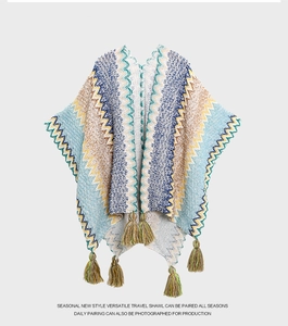 Detail of bohemian knit shawl featuring wave patterns and decorative fringe accents