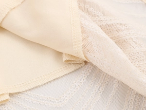 Detailed close-up of beige inner lining and geometric lace mesh fabric sewing quality