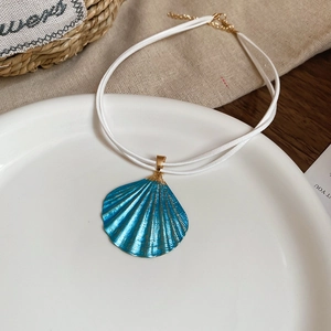 Detailed view of a blue shell pendant necklace with gold texture on a white ceramic plate