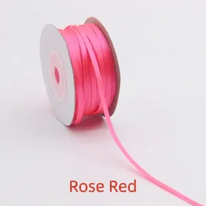 Detailed view of 3mm rose red double-sided satin ribbon roll on a white spool