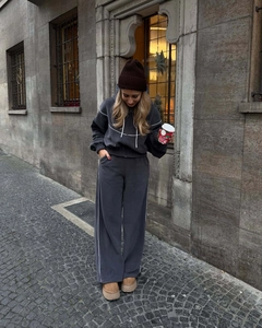 Détail d'un ensemble sweat à capuche zippé gris foncé et pantalon large sur pavés