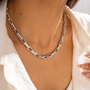 Detail of chunky silver link chain necklace worn on a model with white shirt