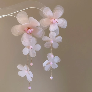 Detail of white chiffon flower tassel earrings with pink beads on delicate gold chains