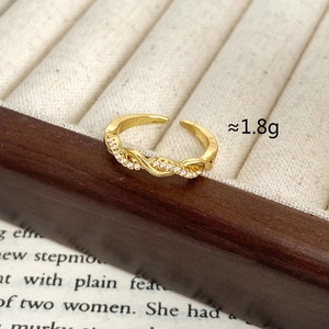 Detail of minimalist gold twisted ring with inlaid zircon and adjustable open band