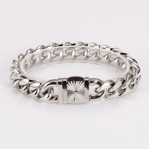 Detail of silver Cuban link bracelet with sunburst engraved clasp on a display stand