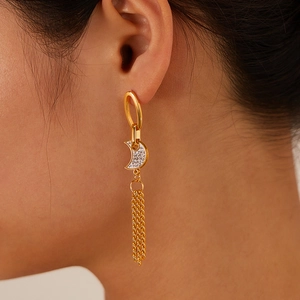Close-up of golden moon-shaped earrings with sparkling cubic zirconia and long tassels