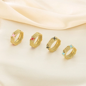 Close-up of four gold twisted rope rings with colorful star charms on silk background