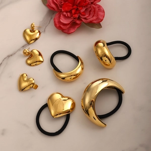 Golden heart and crescent stainless steel hair accessories set on white marble background