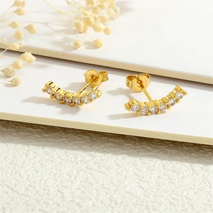 Macro detail of 18K gold plated curved earrings with white cubic zirconia pavé stones