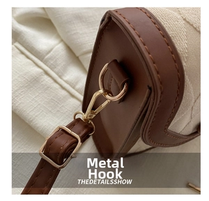 Détail du crochet en métal doré sur le sac à bandoulière en cuir brun et toile
