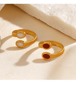 Close-up of golden threaded rings with white and red oval stones on silk fabric