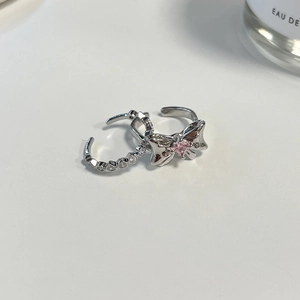 Close-up of silver bow ring with pink gem and a matching pavé diamond band