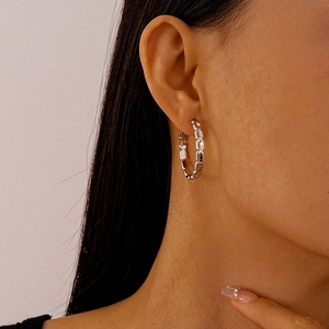 Close-up of silver geometric chain hoop earrings worn by a model for a modern look