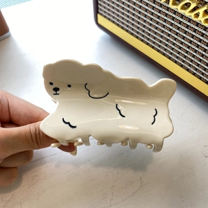 Detail of cream acetate dog hair claw clip with black minimalist outline design