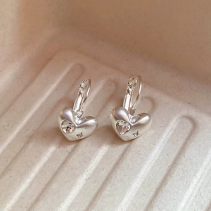 Detailed close-up of heart-shaped silver earring with crystal stone and star engraving